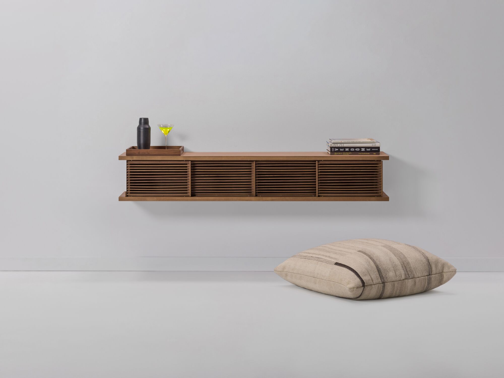 Medium oak floating wall shelf with floor pillow beside it and books on it